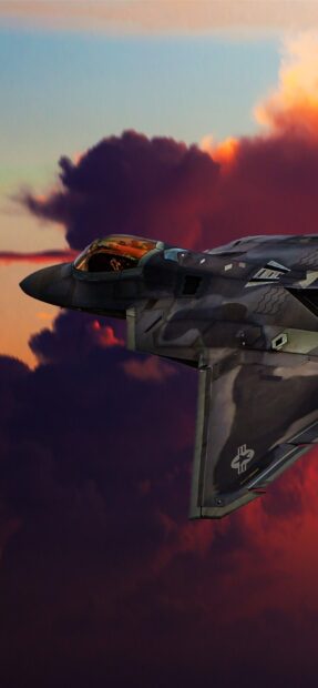 A stealth jet fighter flies through a vibrant sunset sky with dark clouds, 2K Mobile Wallpaper