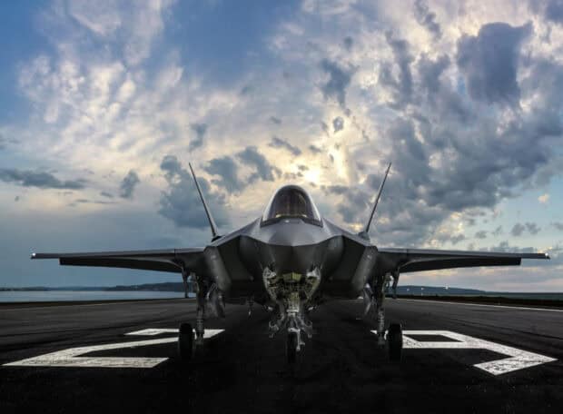 A stealth jet fighter is positioned on the runway under a cloudy sky, HD Desktop Wallpaper