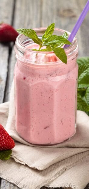 A creamy strawberry milkshake topped with fresh mint leaves in a glass jar, HD Mobile Wallpaper