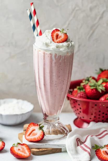 A glass of strawberry milkshake with whipped cream and fresh strawberries on the side, HD Mobile Wallpaper