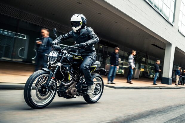 A street bike rider wearing gear is riding through a city street with blurred pedestrians, HD Desktop Wallpaper