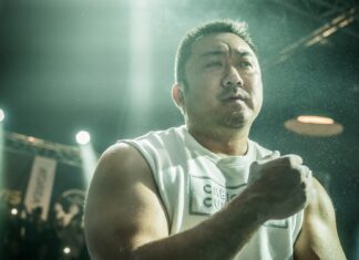 Ma Dong Seok focuses intensely during a fight scene under bright lights, HD Desktop Wallpaper