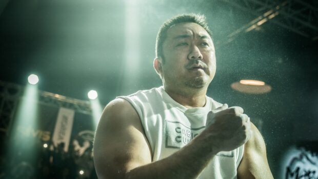 Ma Dong Seok focuses intensely during a fight scene under bright lights, HD Desktop Wallpaper