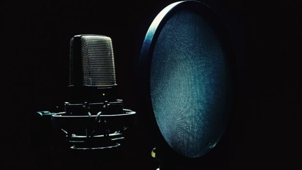 A studio microphone with pop filter is shown ready for recording vocals in a dimly lit setting, 4K Desktop Wallpaper