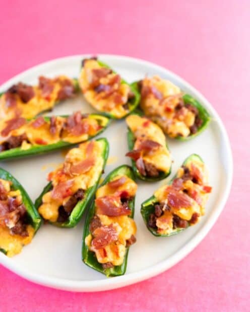 Stuffed jalapeno bites topped with cheese and bacon on a white plate against a pink background, HD Mobile Wallpaper