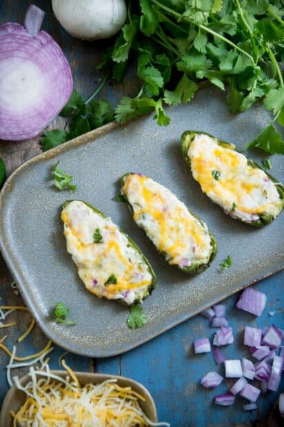 A plate of stuffed jalapeno peppers topped with melted cheese and herbs, 2K Mobile Wallpaper