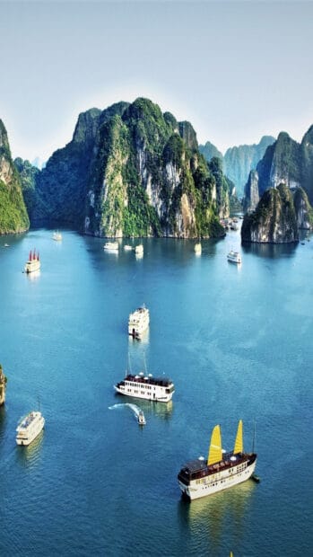 A peaceful seascape in Vietnam features several boats sailing near lush limestone islands, HD Phone Wallpaper