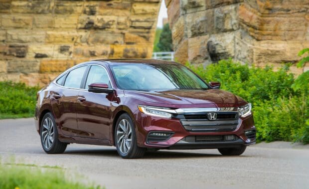 A maroon Honda Insight drives past a stone wall on a sunny day with greenery around, HD Desktop Wallpaper