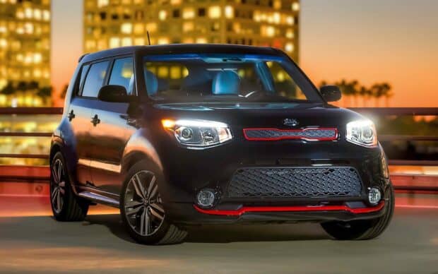 A black Kia car is parked with city lights glowing at sunset in the background showing Kia Wallpapers 4K and Full HD, HD Desktop Wallpaper