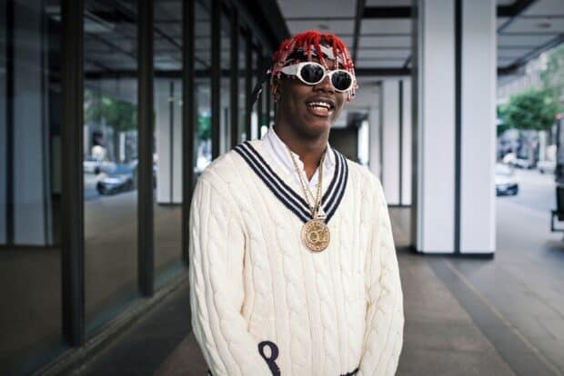 Lil Yachty is wearing sunglasses and a white sweater with a gold necklace in an urban setting, HD Desktop Wallpaper