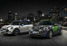 Two stylish Mini Cooper cars are parked in front of a city skyline at night, 2K Desktop Wallpaper