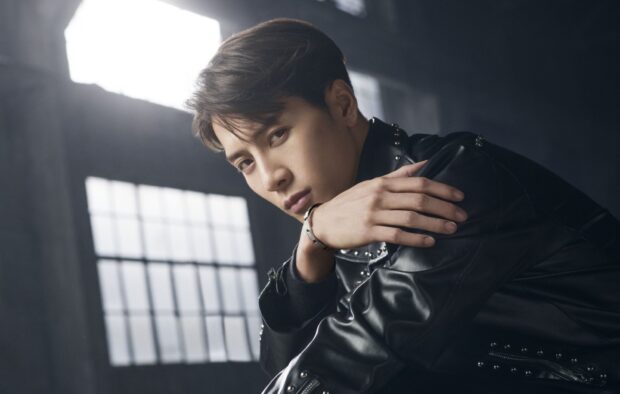 A stylish man wearing a black leather jacket poses thoughtfully in front of a bright window, HD PC Wallpaper