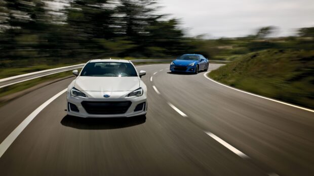 Two Subaru Brz cars are racing on a winding mountain road surrounded by trees, 4K Desktop Wallpaper