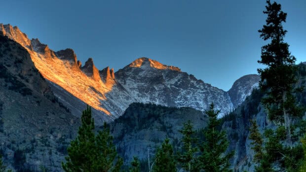 The sun casts a golden glow on the rocky peaks in Rocky Mountain National Park, 2K Desktop Wallpaper