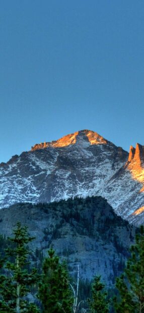 The sunlit peak of Rocky Mountain National Park rises above green forests under a clear blue sky, HD Mobile Wallpaper