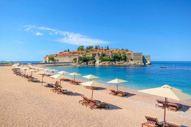A sunny beach scene with umbrellas and a view of the Montenegro coast, 2K Desktop Wallpaper