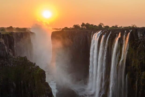 The sun sets over Devils Pool Zambia with mist rising from the falls, HD Desktop Wallpaper