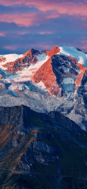 The glacier mountain is glowing under the pink sunset sky with sharp rocky peaks and snowy slopes, 2K Mobile Wallpaper