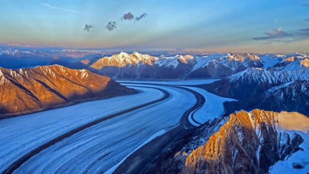 The winding glacier is surrounded by snow covered peaks at sunset, HD Desktop Wallpaper
