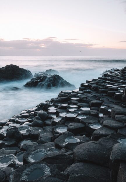 The Giants Causeway shows hexagonal stone columns by the sea under a cloudy sky, 2K Mobile Wallpaper