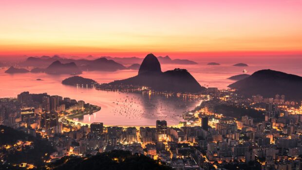The sunset over Rio De Janerio shows the bay with Sugarloaf Mountain and city lights, 4K Desktop Wallpaper