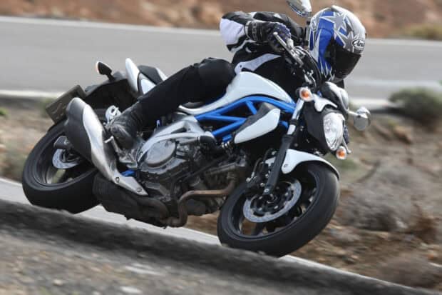 A rider leans while taking a sharp turn on a Suzuki SV650 motorcycle, HD Desktop Wallpaper