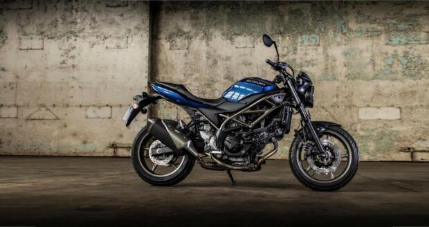 A blue Suzuki SV650 motorcycle stands against a textured wall in an empty room, 4K Desktop Wallpaper