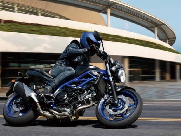 A rider is leaning into a turn on a Suzuki Sv650 motorcycle on a city street, HD Desktop Wallpaper