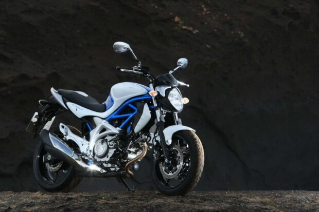 A Suzuki Sv650 stands on a rocky surface with a dark background, HD Desktop Wallpaper