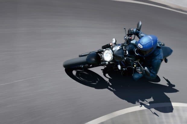 A rider wearing a blue helmet is leaning into a curve on the Suzuki Sv650 motorcycle, HD Desktop Wallpaper