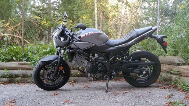 A black Suzuki Sv650 motorcycle parked on a road near greenery, HD Desktop Wallpaper