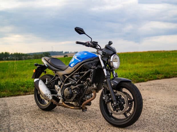 A blue Suzuki Sv650 is parked on a countryside road with a cloudy sky, HD Desktop Wallpaper