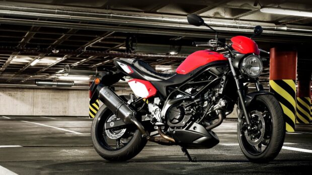 A red Suzuki Sv650 motorcycle is parked in an underground garage showcasing its design and details, HD Desktop Wallpaper