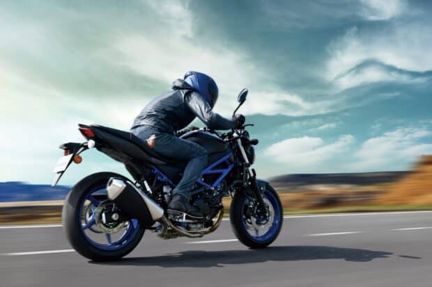 A rider on a Suzuki Sv650 wearing protective gear rides swiftly under a cloudy sky, HD Desktop Wallpaper