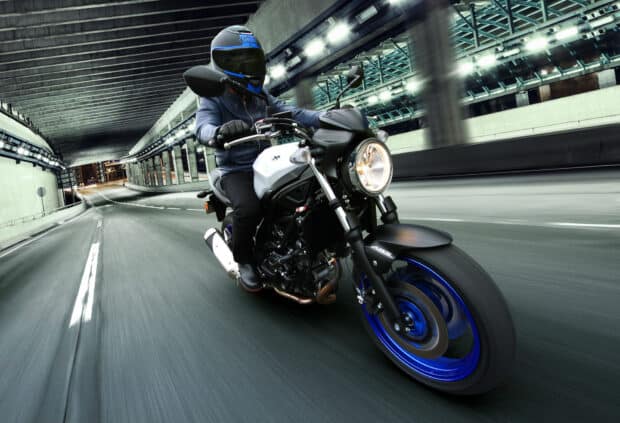 A rider on a Suzuki Sv650 is riding quickly through an illuminated tunnel at night, HD Desktop Wallpaper