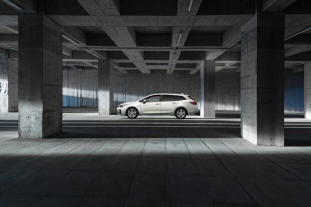 A white Suzuki Swace is parked inside a spacious concrete structure with pillars and shadows, HD Desktop Wallpaper
