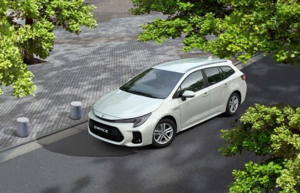 A white Suzuki Swace is parked on a city street surrounded by green trees, HD Desktop Wallpaper