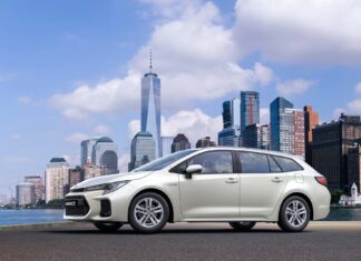 A white Suzuki Swace is parked near a city waterfront with skyscrapers in the background, HD Desktop Wallpaper