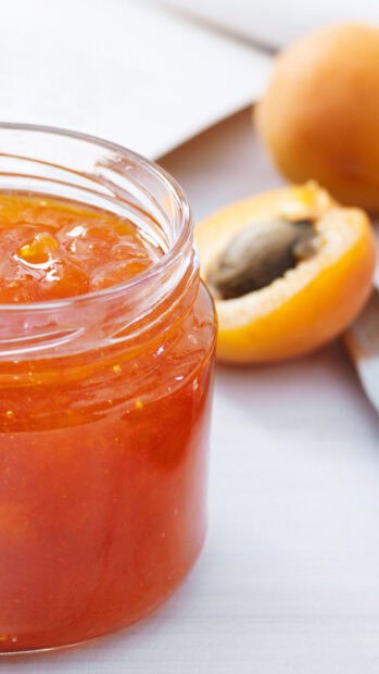 A close up of apricot jam with fresh apricot fruit halves on a white surface, HD Phone Wallpaper