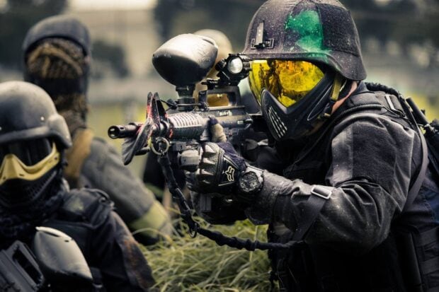 A paintball player in tactical gear aiming carefully during a match, HD Desktop Wallpaper