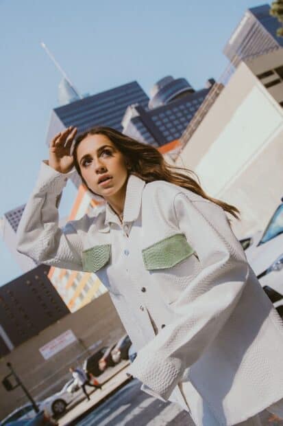 Tate Mcrae wears a textured white jacket with green accents while posing on a city street, HD Mobile Wallpaper