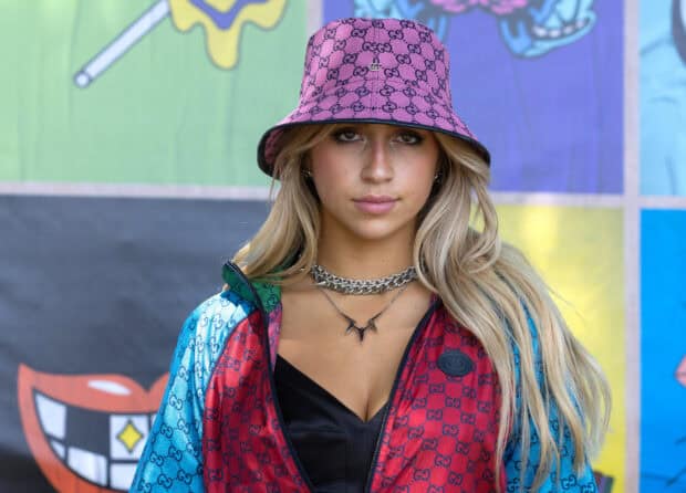 Tate Mcrae stands confidently wearing a vibrant Gucci jacket and pink bucket hat, HD Desktop Wallpaper