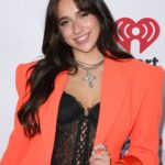 Tate Mcrae wears an orange blazer and black lace top while smiling at an event, HD Desktop Wallpaper