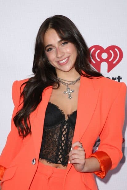 Tate Mcrae wears an orange blazer and black lace top while smiling at an event, HD Desktop Wallpaper