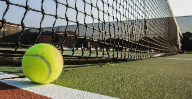 A tennis ball lies close to the net on an outdoor tennis court, 2K Desktop Wallpaper