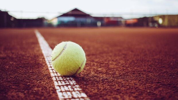 A tennis ball lies on the white line of a clay court ready for play, HD Desktop Wallpaper