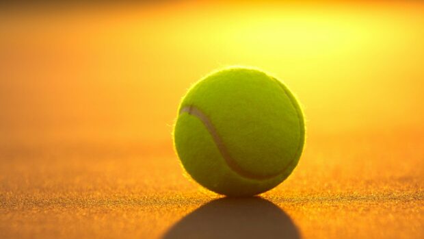A tennis ball resting on the court with the sun setting in the background, HD Desktop Wallpaper