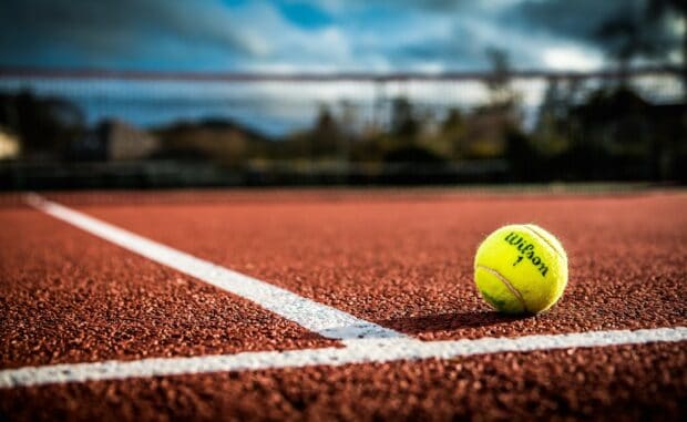 A tennis ball lies near the white line on the clay court in this tennis scene, HD Desktop Wallpaper