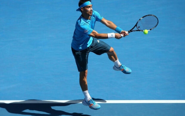 A tennis player in blue sportswear is focused on returning the ball during a match, HD Desktop Wallpaper
