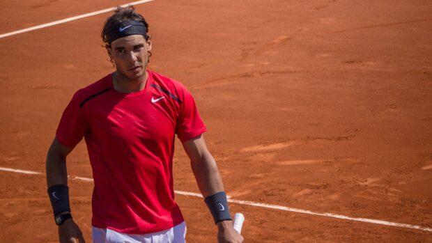 A tennis player wearing a red shirt is standing on the clay court at the French Open Roland Garros, 4K Desktop Wallpaper